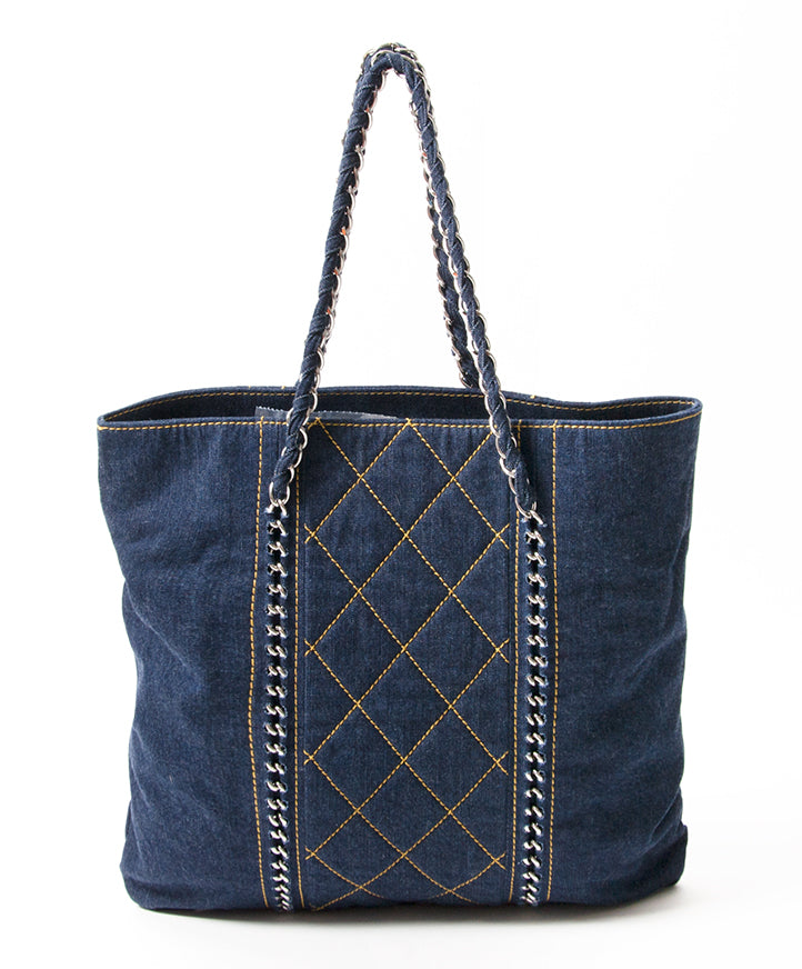 This is a Chanel tote in blue denim with contrast ochre stitching. Silver-tone chain hardware.