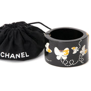 CHANEL RESIN BUTTERFLY CUFF A rare Chanel cuff made of black resin with cheery butterfly and logo print.