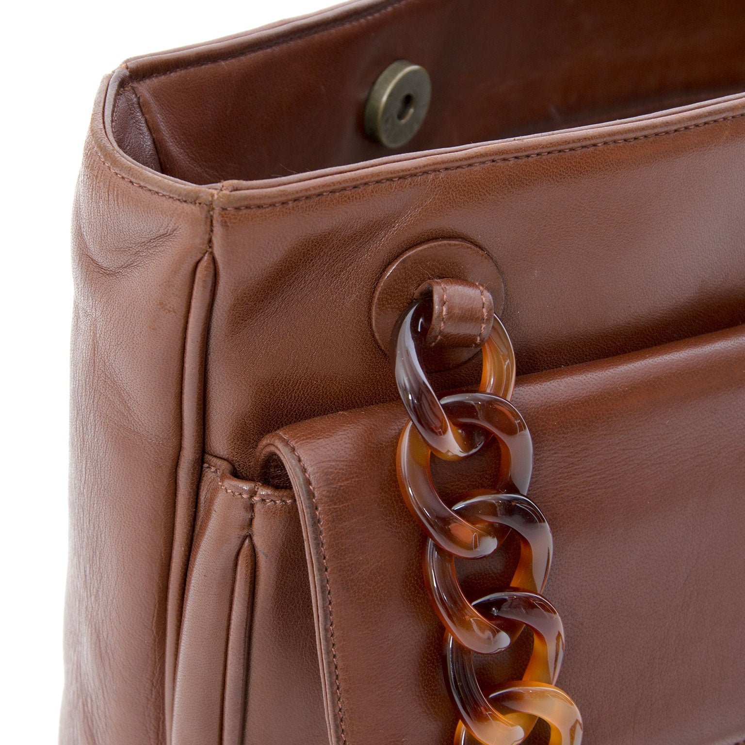 Chanel Nut Brown Tortoise Chain Tote Chanel handbag with chain in brownish tints. Features a pocket on the front with Chanel closure in the material of the chain. Chanel logo is depicted on the backside of the bag. The interior features a major pocket a