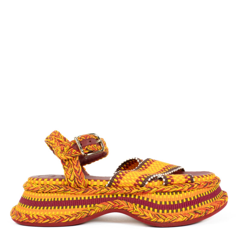 The Chloé Meril sandals in orange feature a handwoven multicolor cotton design with a wavy, chunky platform and adjustable ankle strap. Buy now on Labellov.com.