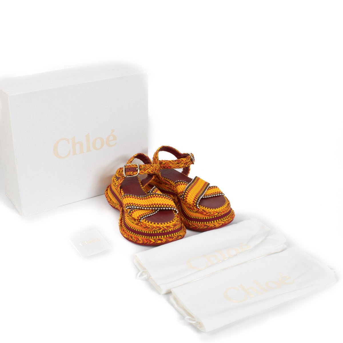 The Chloé Meril sandals in orange feature a handwoven multicolor cotton design with a wavy, chunky platform and adjustable ankle strap. Buy now on Labellov.com.