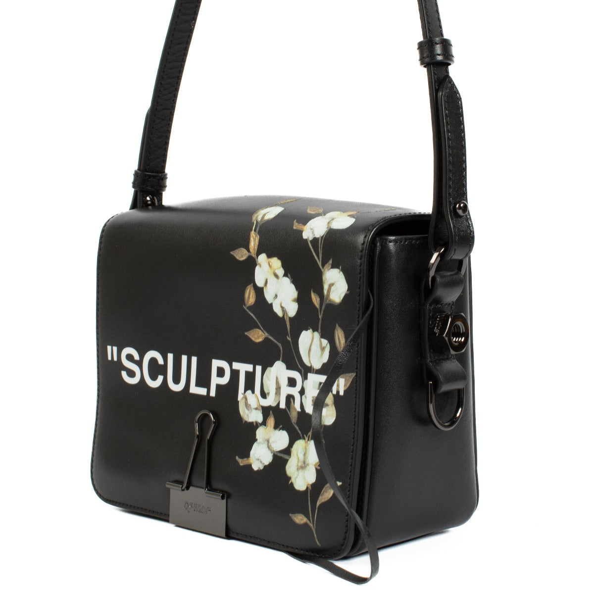 Black leather shoulder bag with cotton flower print, Off-White cut-out strap, 'SCULPTURE' text print, magnetic closure, and binder clip detail at the front. Includes one black shoulder strap. Shop now on Labellov.com.