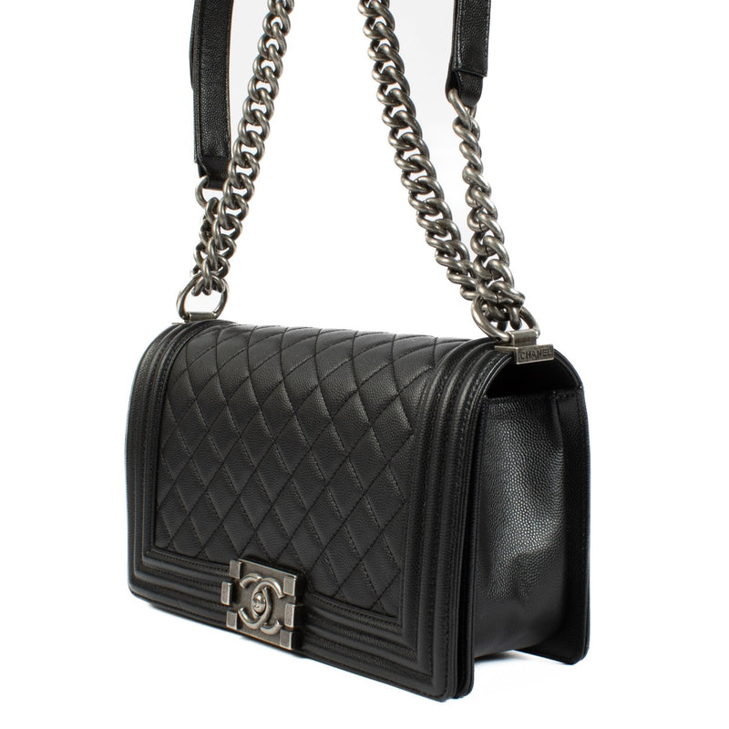 Chanel Boy Bag in black, featuring quilted leather, a signature push-lock closure, and a chunky chain strap. Shop now on Labellov.com.