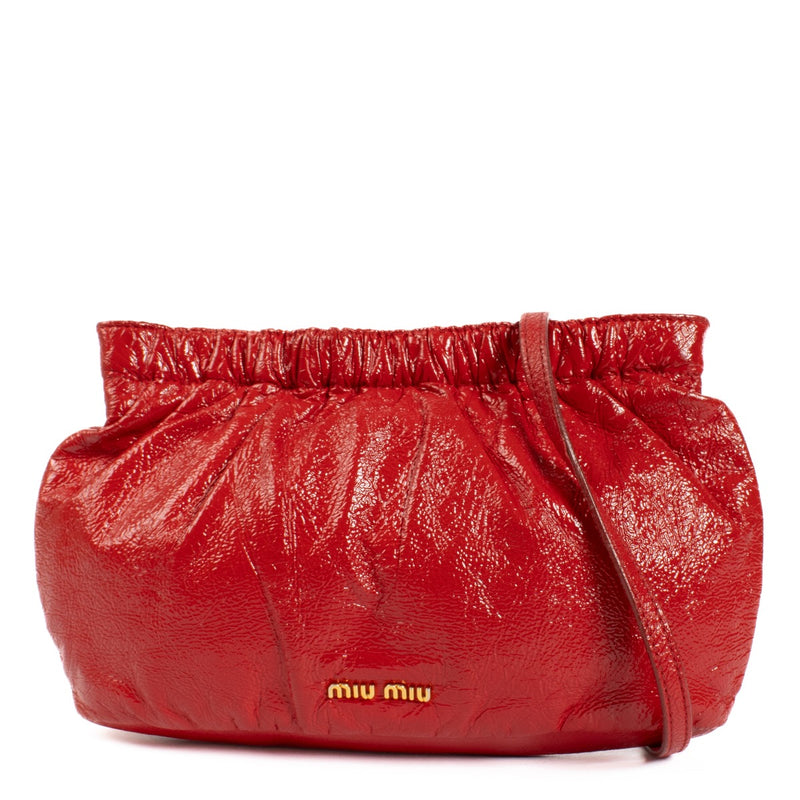 The Miu Miu Red Shoulder Bag in glossy red leather features gold hardware and the iconic Miu Miu logo on the front. Its pouch shape adds a modern, chic touch to the design. Shop now at Labellov.