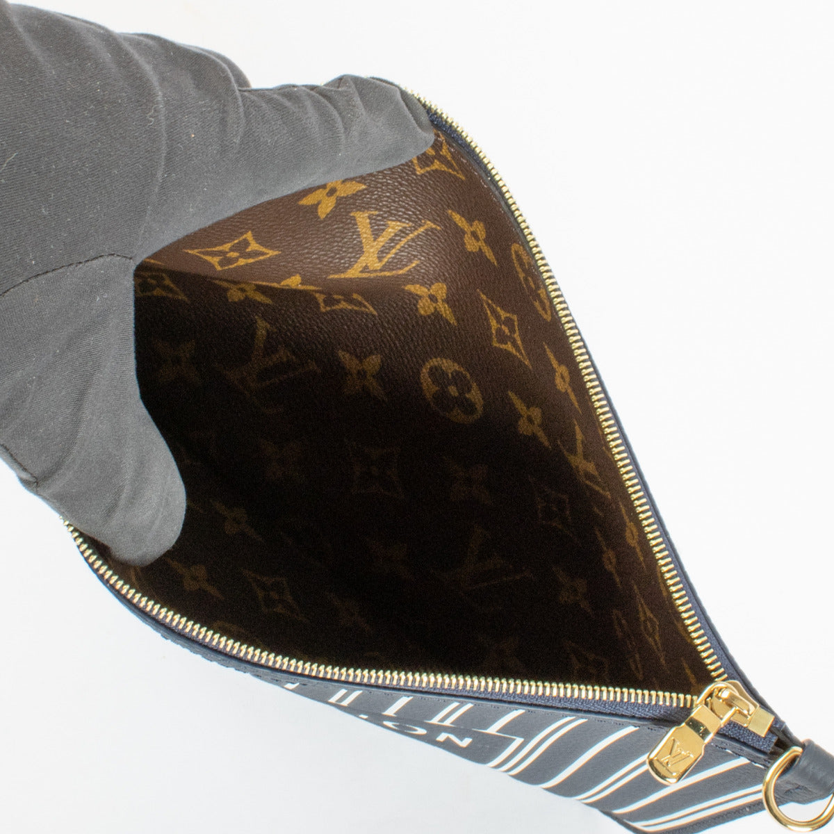 The Louis Vuitton Neverfull Inside Out Clutch reinterprets the beloved Neverfull tote in a sophisticated navy palette, elevated by the iconic reversible structure. Interior in monogram canvas. Gold-toned hardware. — This clutch pochette is perfect for