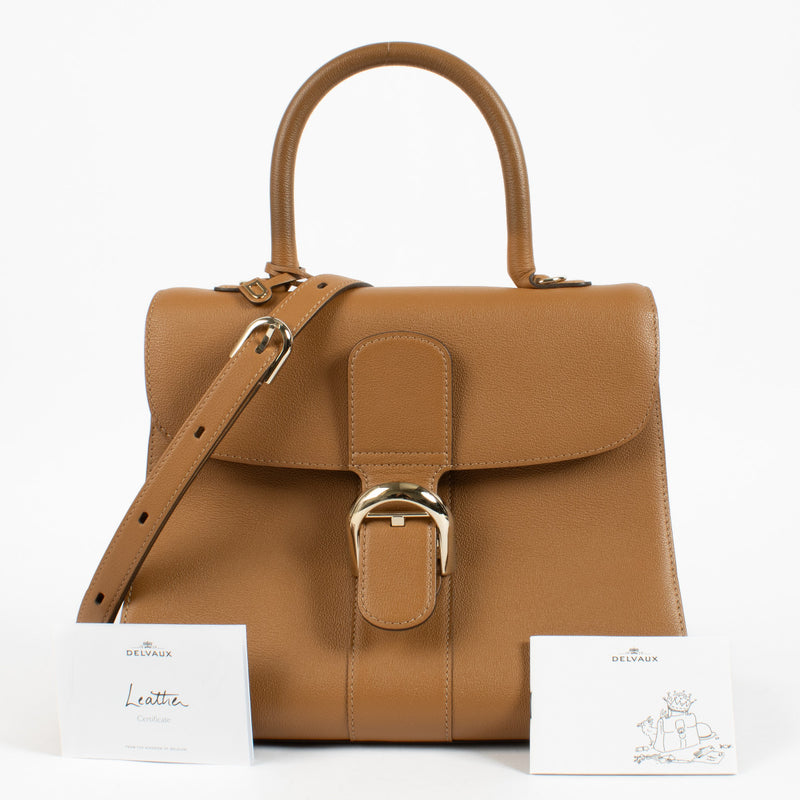 Front view of Delvaux Brillant MM in warm brown leather showcasing signature curved silhouette.