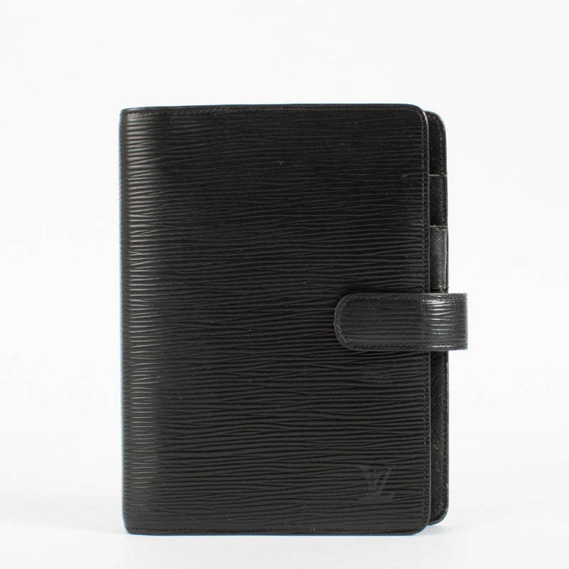 Elevate your everyday organization with the timeless sophistication of this Louis Vuitton Medium Agenda Cover in signature Black Epi leather. Crafted in the Maison’s iconic textured calfskin, this agenda strikes a refined balance between utility and style