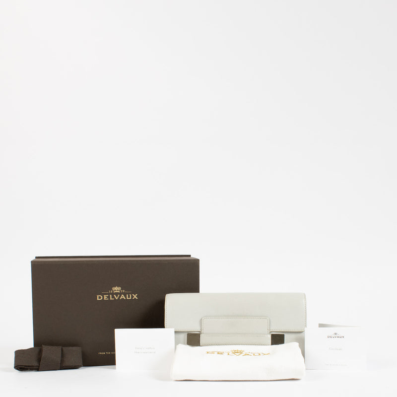 Crafted from smooth grey box calf leather, this structured wallet balances minimalist form with exceptional functionality. The sleek silhouette is accented by a distinctive rectangular flap with metallic detailing, offering a subtle yet luxurious nod to t
