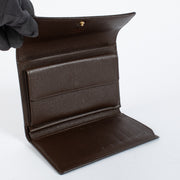 Louis Vuitton Damier Ebene Trésor Wallet in brown checkered canvas with gold-tone snap closure and original dust bag at Labellov.com.