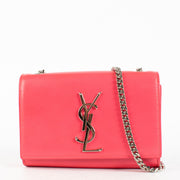 Effortlessly bold and unapologetically chic, the Saint Laurent Kate Small Bag in vibrant pink is a standout piece for lovers of high-impact minimalism. Crafted in smooth calfskin leather, this structured silhouette is adorned with the iconic interlaced YS
