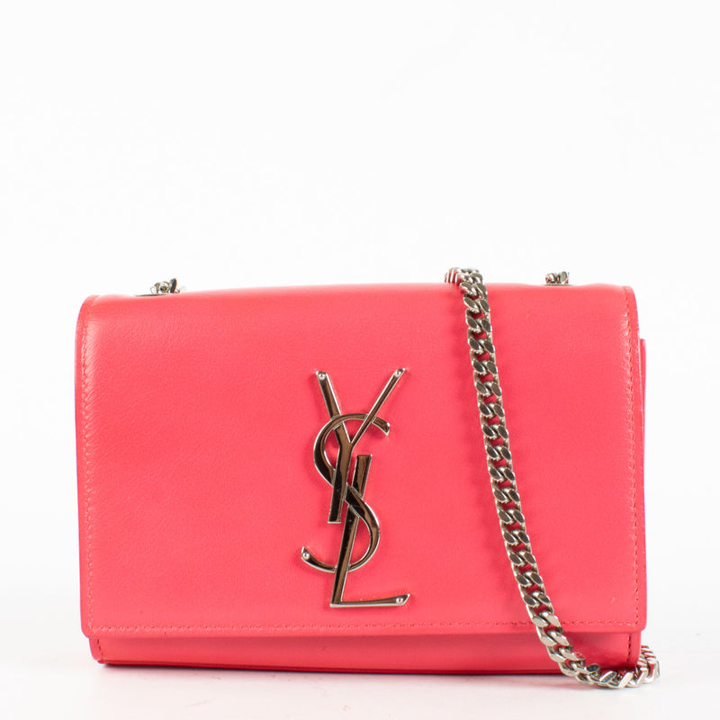 Effortlessly bold and unapologetically chic, the Saint Laurent Kate Small Bag in vibrant pink is a standout piece for lovers of high-impact minimalism. Crafted in smooth calfskin leather, this structured silhouette is adorned with the iconic interlaced YS